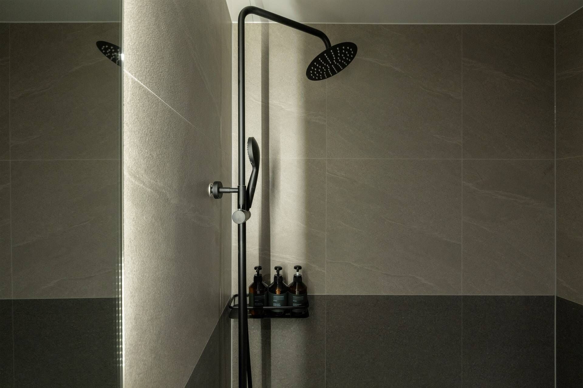 A modern shower with a handheld showerhead and a wall-mounted rain showerhead.