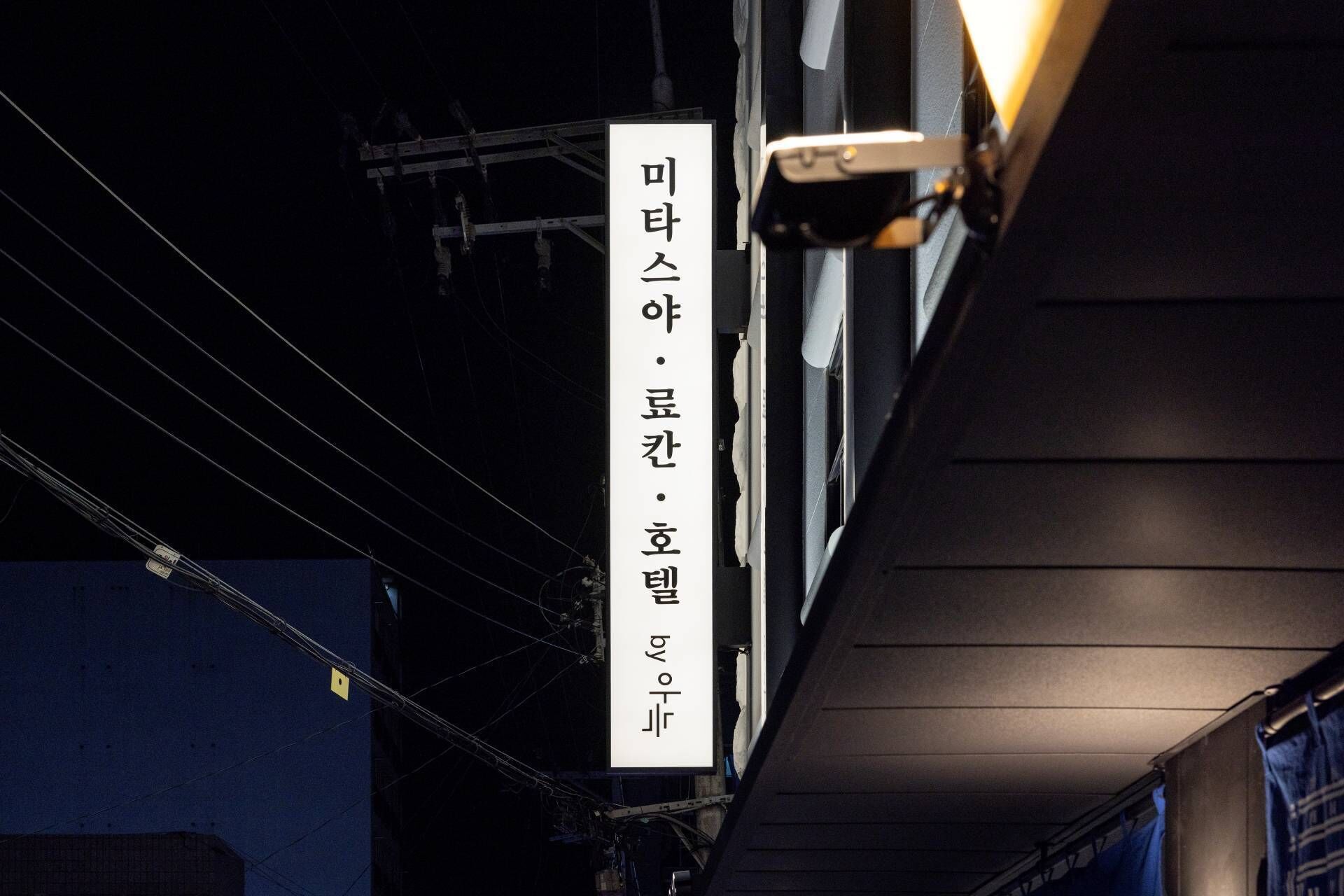 Un letrero vertical con texto coreano, probablemente indicando el nombre de un negocio o establecimiento.