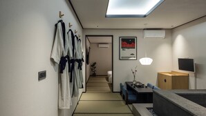 Een modern interieur met een gang die naar een kamer leidt, een eethoek met een lage tafel en stoelen, en een zithoek met een bank.
