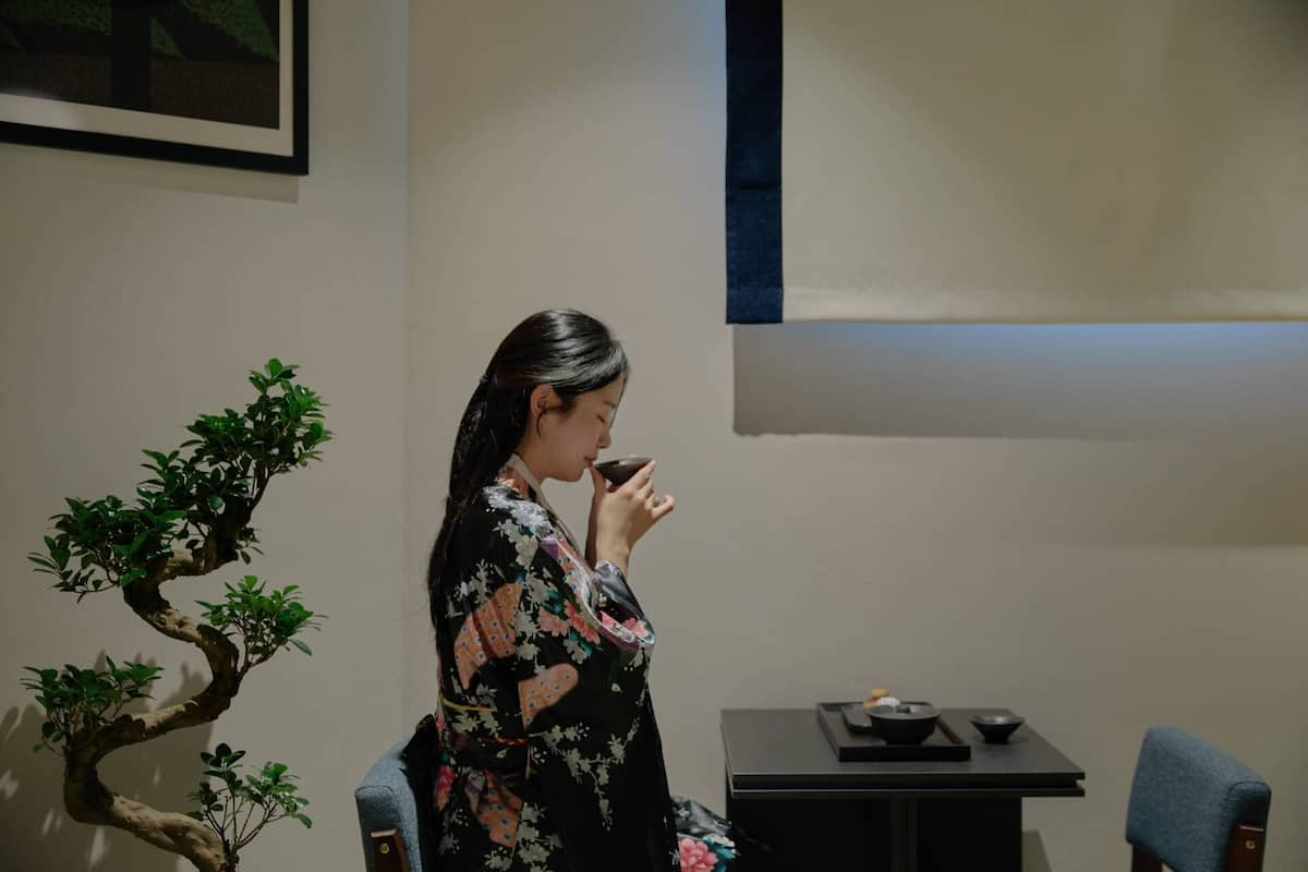 Ein Zimmer mit Bonsai-Baum, Tisch mit Tee-Service und einem Stuhl.