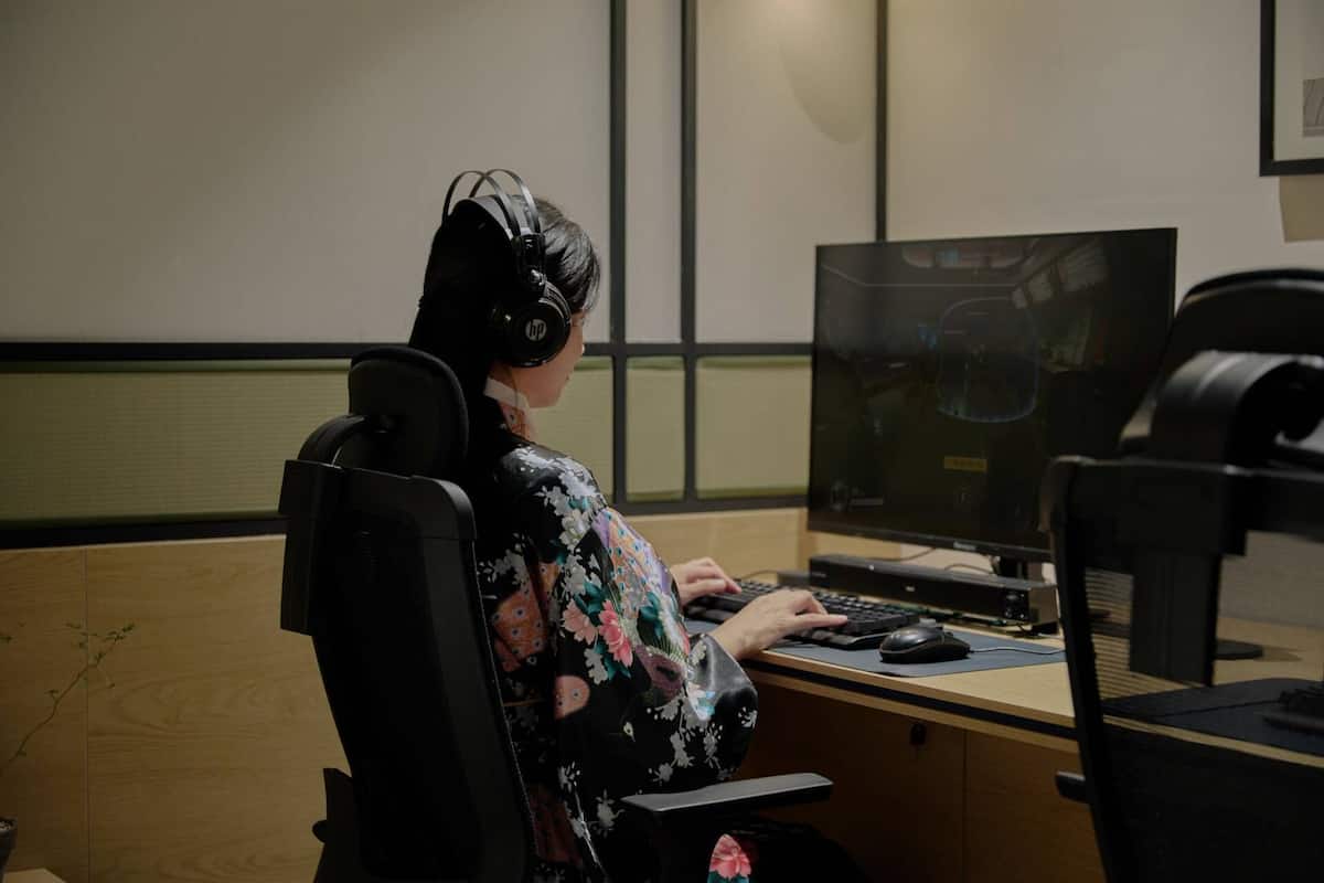 Eine Person benutzt einen Computer in einem Raum mit einem Holztisch und einem großen Bildschirm.