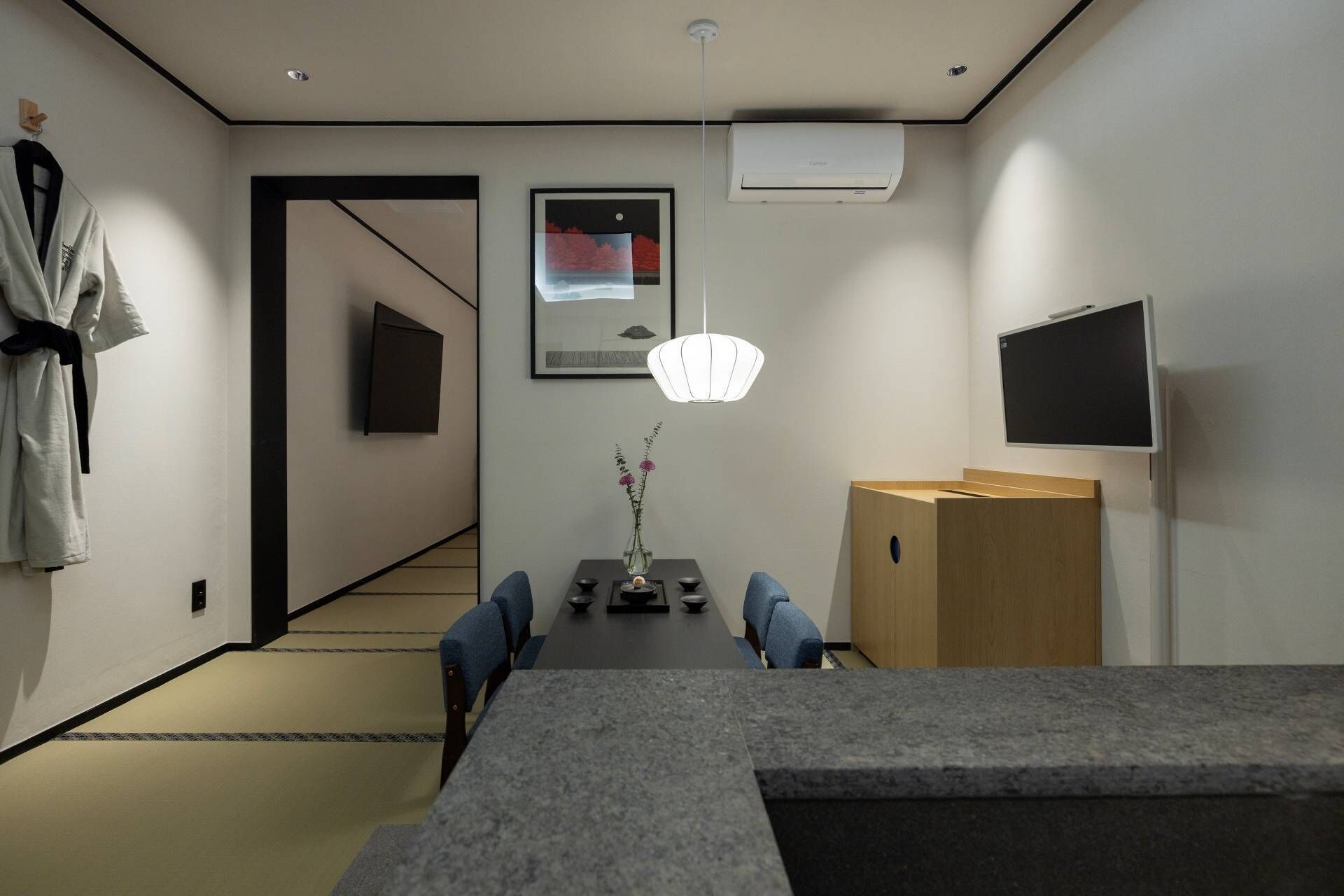 Ein modernes Interieur mit Essbereich, Fernseher und einem aufgehängten Kunstwerk.