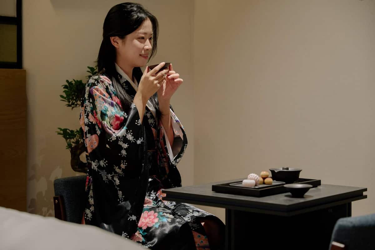Eine Person in einem Kimono sitzt an einem Tisch mit einem traditionellen Tee-Set.