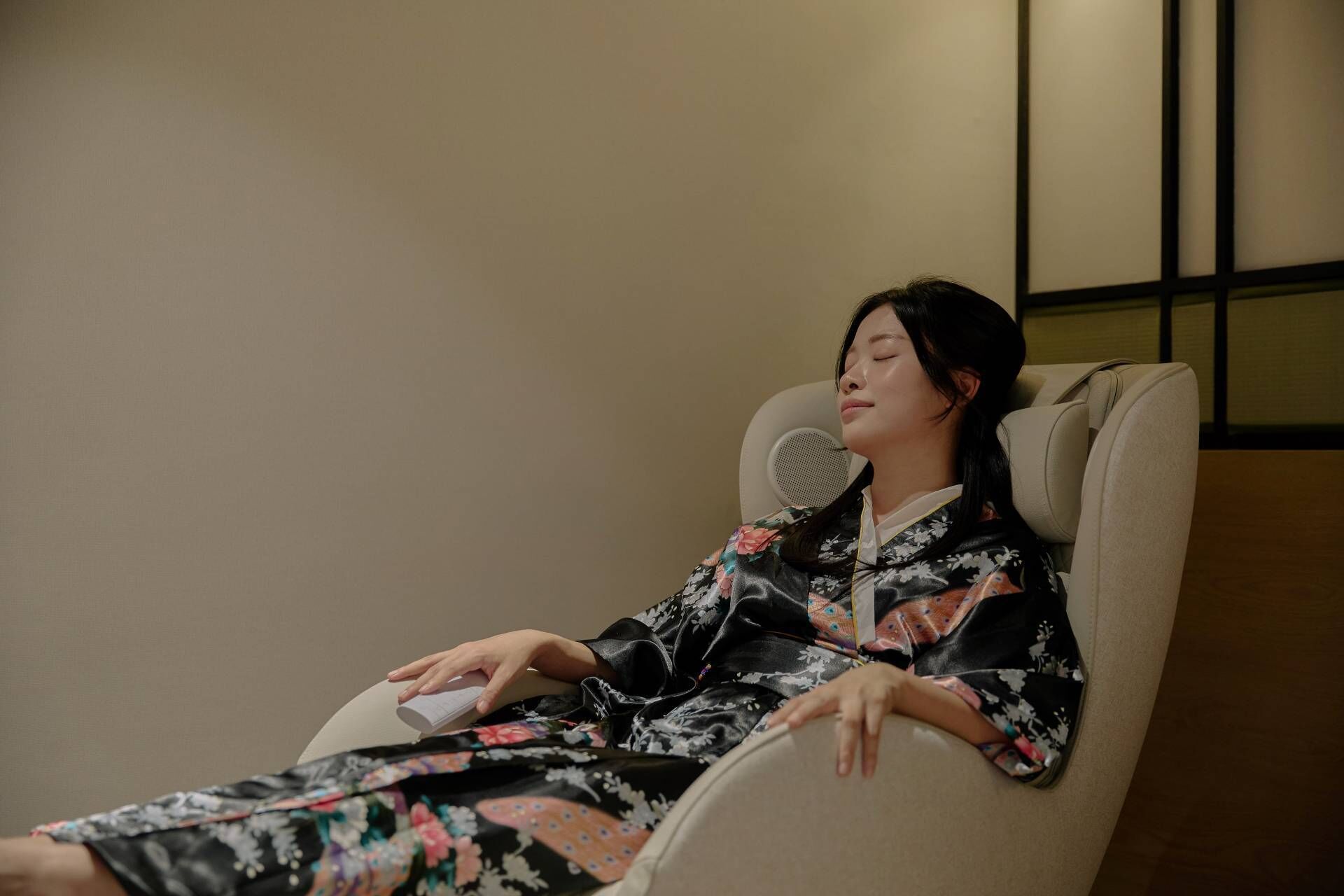 Una persona con un vestido floral sentada en una silla con un micrófono.