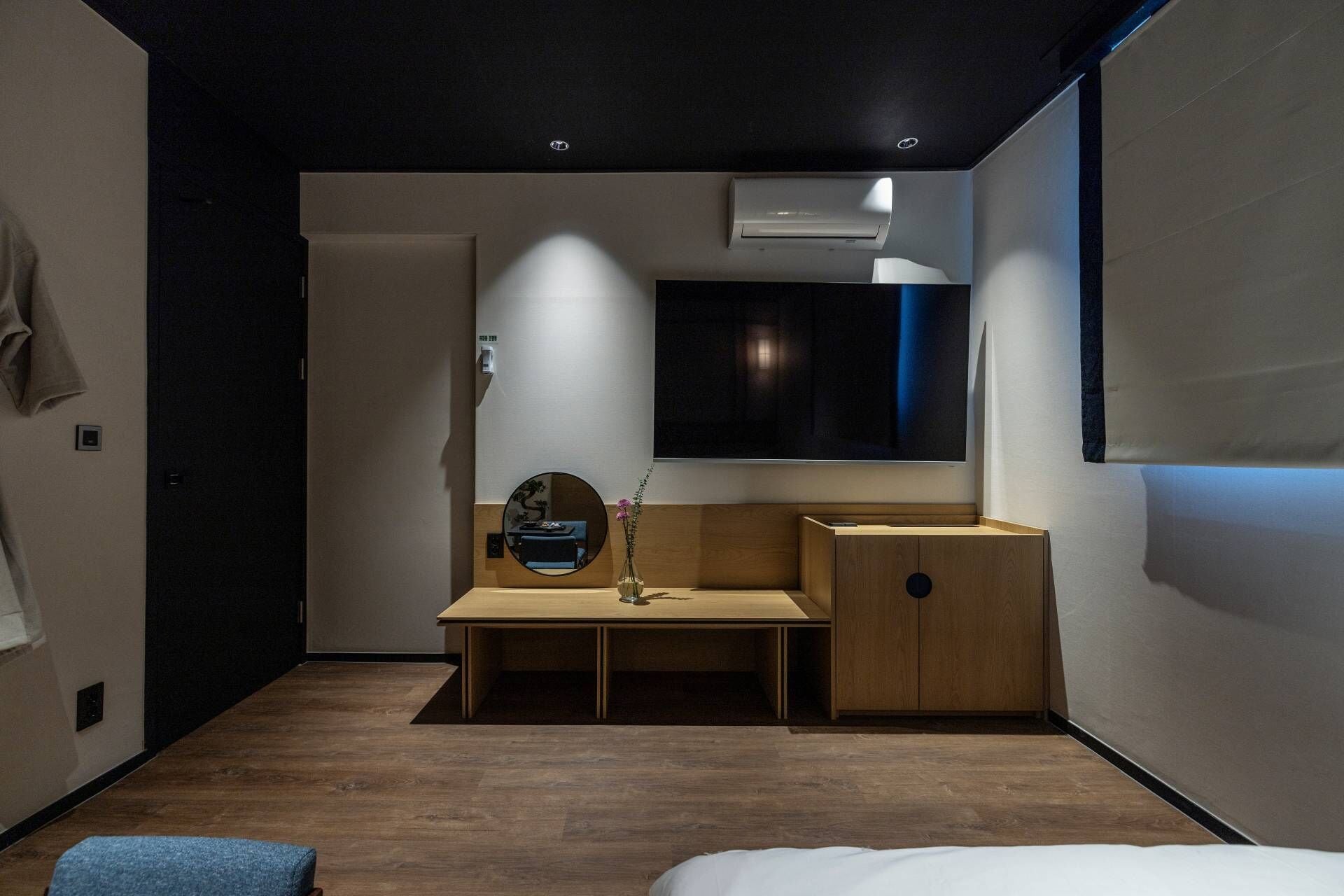 Un dormitorio moderno con un escritorio de madera, un espejo y una cama.