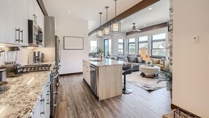 A modern kitchen with a central island, stainless steel appliances, and pendant lighting. - AC in Downtown 2/2 with Mountain Views and easy access! (Winter Park)