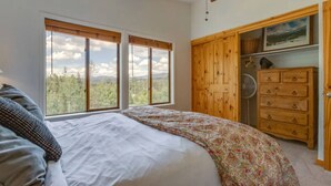 Una camera da letto con un letto grande, un armadio in legno e vista sull'esterno attraverso la finestra.