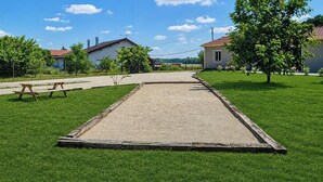 A courtyard with a sand court, a picnic table, and houses in the background. - The Crested Grebe. In the countryside between Lake Der, the lakes, and the forests of the East (Joncreuil)