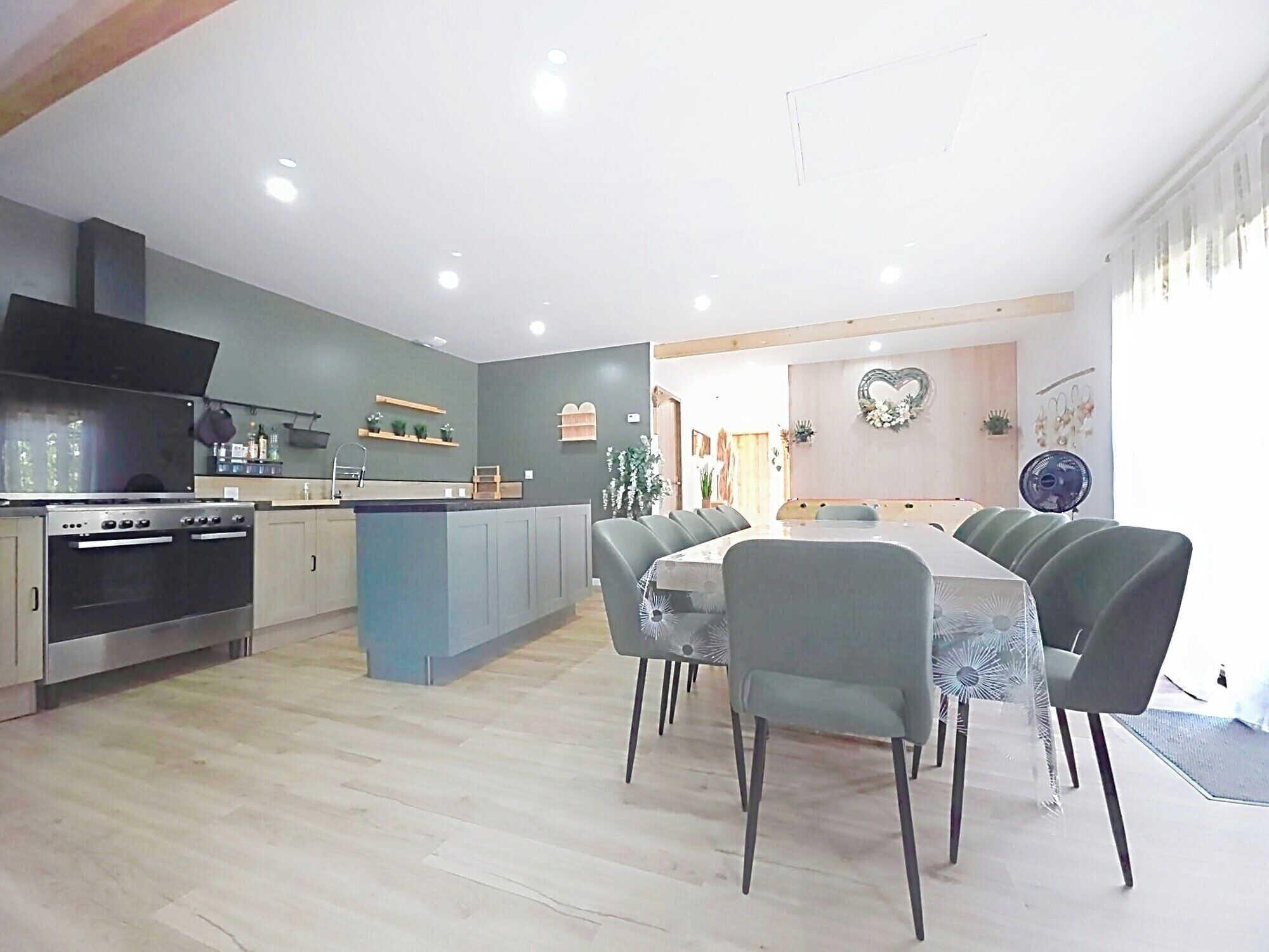 Una cocina moderna con una isla central, comedor con sillas y un horno a la vista.