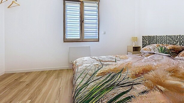 A bedroom with a bed, a window with blinds, a bedside table, and a nightstand. - The Crested Grebe. In the countryside between Lake Der, the lakes, and the forests of the East (Joncreuil)
