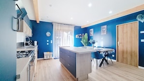 Une cuisine moderne dotée d’un îlot central, de meubles en bois et d’un coin repas avec des chaises bleues.