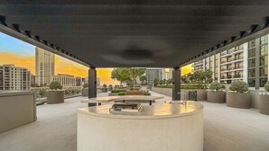 Una terrazza sul tetto con una zona salotto circolare, piante in vaso e vista sugli edifici circostanti.