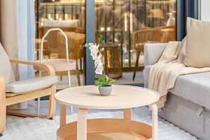 A cozy living area with a round wooden table, a sofa, and two chairs. A potted plant is on the table. - FIRST CLASS | 1BR | Creek Escape · Modern Elegance (Dubai Creek Harbour)