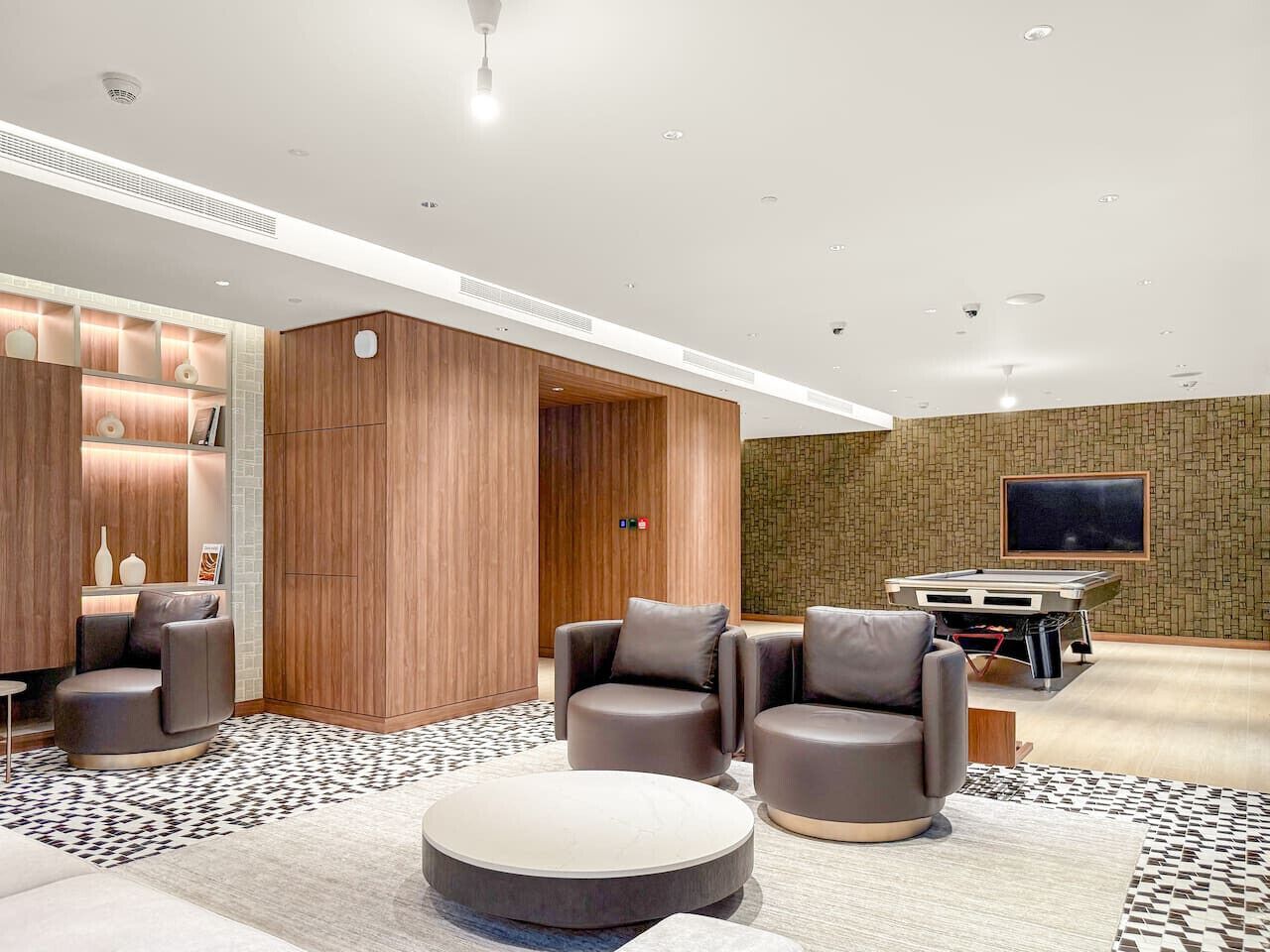 Eine moderne Hotelhalle mit Ledersofas, einem Billardtisch und einem Flachbildfernseher.
