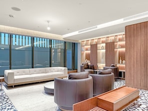 A modern living room with a white sofa, grey armchairs, and a wooden coffee table. - FIRST CLASS | 2BR | The Crest • Near Attractions (Meydan)