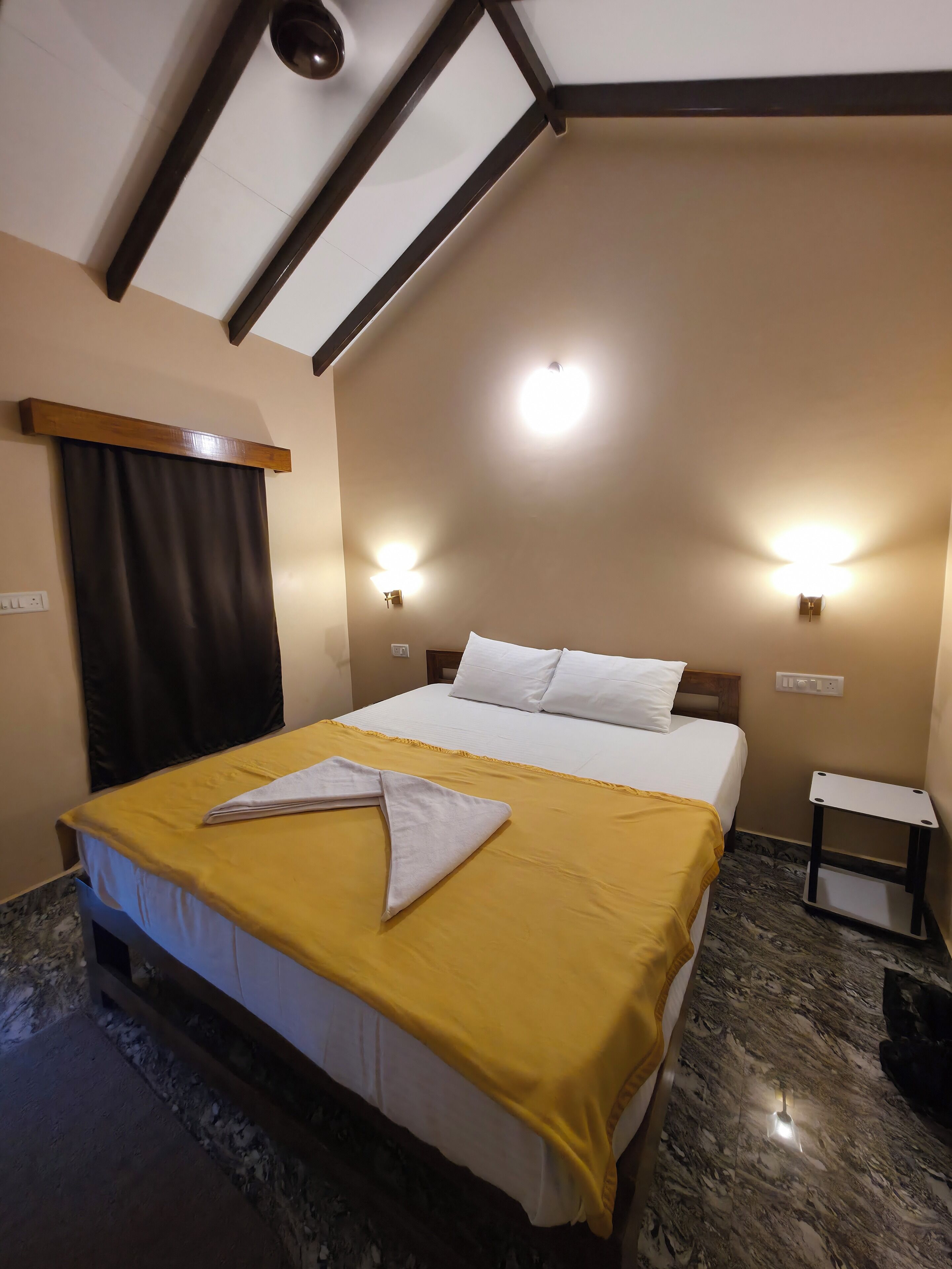 Una habitación de hotel con cama, mesita de noche y lámpara de techo.