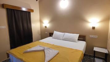Una habitación de hotel con cama, mesita de noche y lámpara de techo.