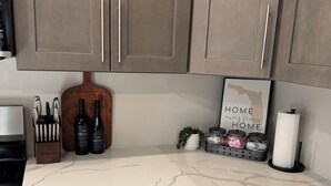 A kitchen with white cabinets, a marble countertop, and a sign that reads "HOME away from HOME". - Coastal Haven-New 3BR/2BA Home, near Beaches+Fenced Yard, Pet-Friendly! (Pensacola)