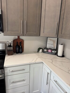 A kitchen with white cabinets, a marble countertop, and a sign that reads "HOME away from HOME".