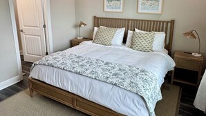 A bedroom with a bed, two bedside tables, a ceiling fan, and two framed pictures on the wall. - Coastal Haven-New 3BR/2BA Home, near Beaches+Fenced Yard, Pet-Friendly! (Pensacola)