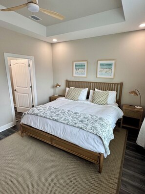 Ein Schlafzimmer mit einem Bett, zwei Nachttischen, einem Deckenventilator und zwei gerahmten Bildern an der Wand.