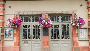 Une façade d’immeuble avec une double porte, une enseigne indiquant « PICTURED DROME » et des jardinières suspendues.