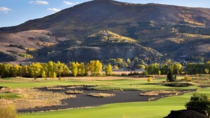 Ein Golfplatz mit Bergblick, Teichen und Herbstlaub.