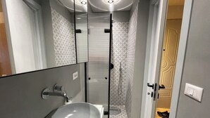 A modern bathroom with a large sink, glass shower enclosure, and patterned tiles. - Piazza Delux Downtown Cozy Studio (Tirana)