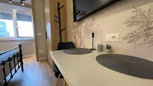 A modern dining area with a white table, black chairs, and a decorative wall with floral patterns. - Piazza Delux Downtown Cozy Studio (Tirana)