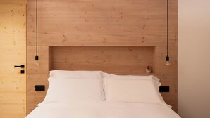 Een slaapkamer met een houten hoofdbord, twee nachtkastjes en een kleine vaas met bloemen.