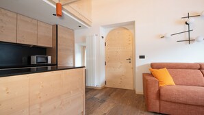 Een moderne keuken met houten kastjes en een zwart aanrecht, een magnetron, en een houten deur naar een andere kamer.