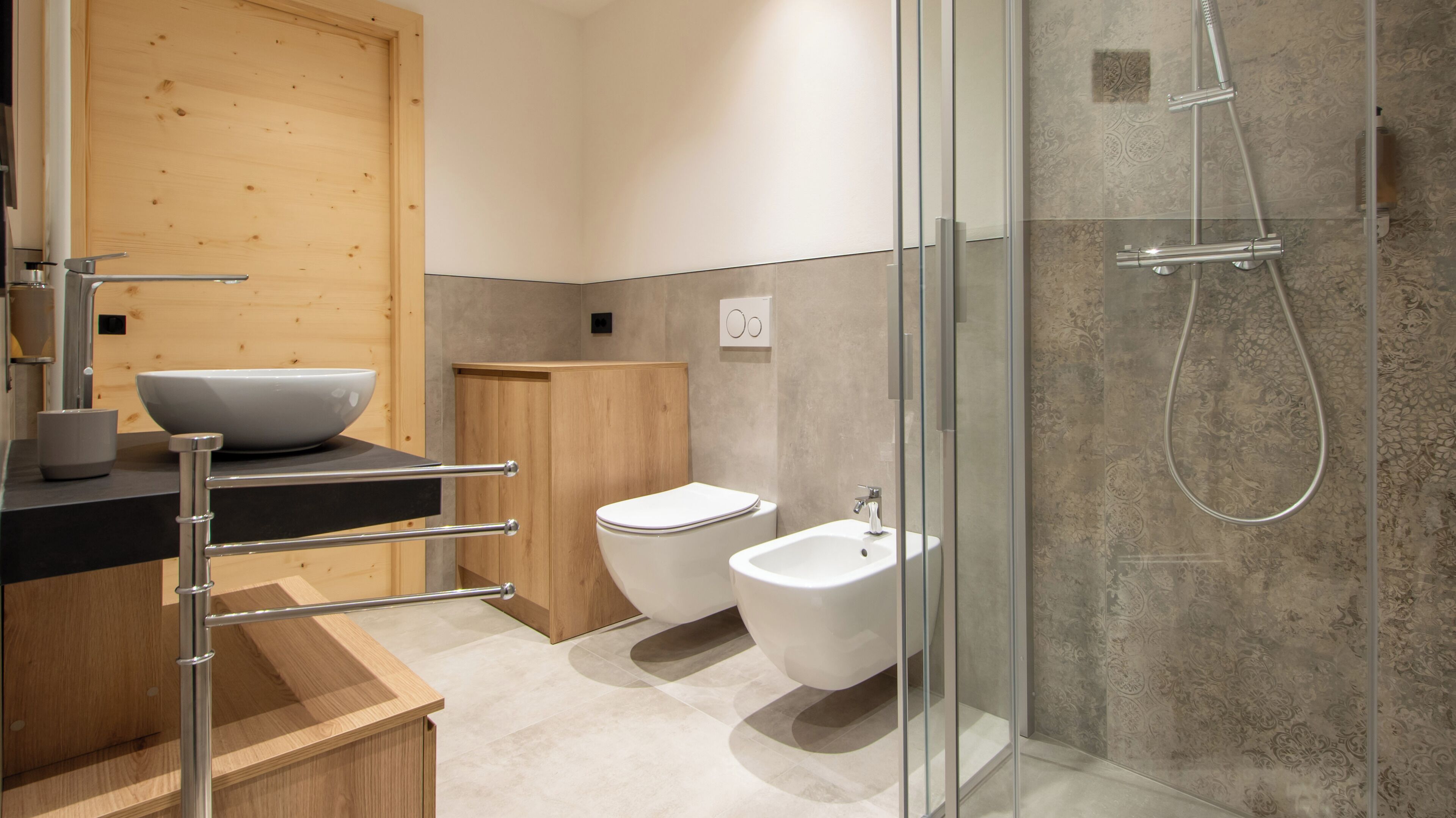 A modern bathroom with a glass-enclosed shower, a wooden vanity, a bidet, and a large sink.