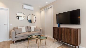 Een moderne woonkamer met een bank, twee bijzettafels, een televisie en een houten kast.