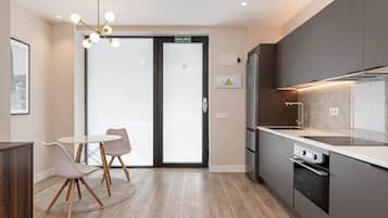 Een moderne keuken met een inbouwoven, een spoelbak en een eethoek met tafel en stoelen.