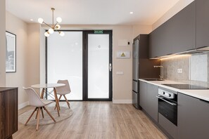 A modern kitchen with a built-in oven, a sink, and a dining area with a table and chairs. - Waou Essence I Bernabeu - Short Term Rental (Madrid)