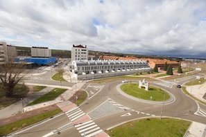 A modern building with a curved facade, a roundabout, and surrounding greenery. - HOSTAL VIA LACTEA (Burgos)