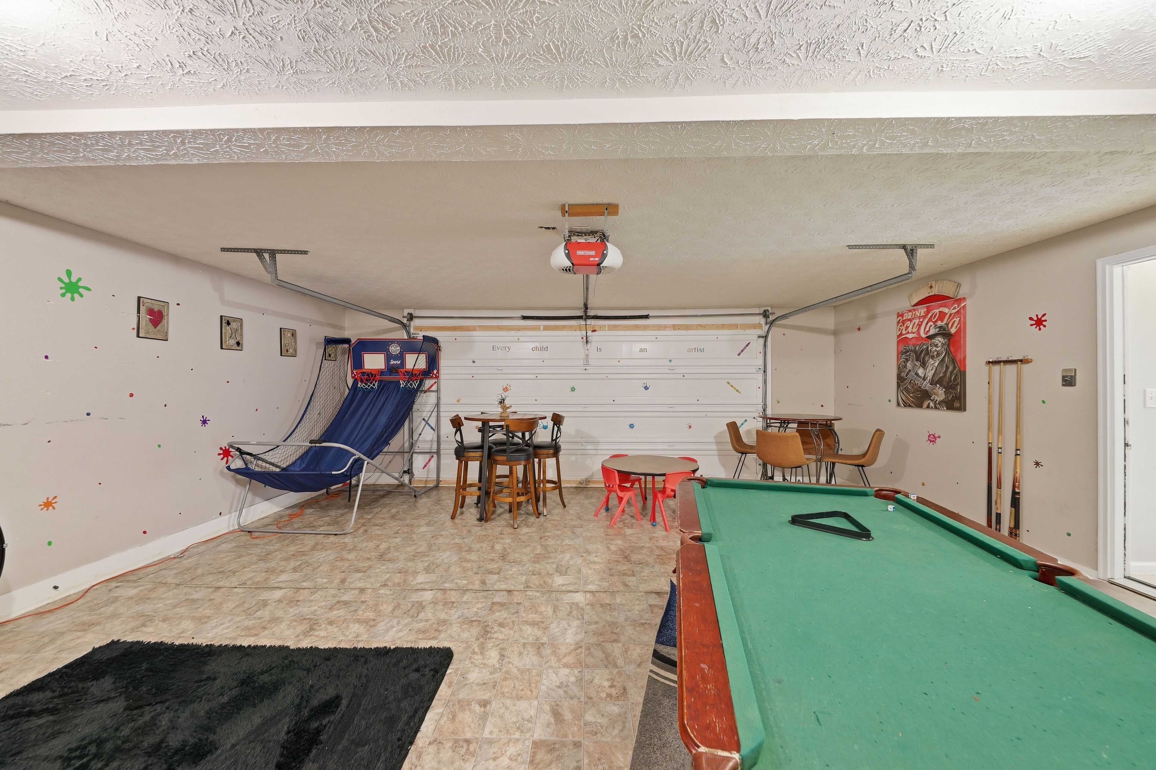 A pool table, a trampoline, and a dining area with chairs and a table.