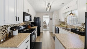 Une cuisine moderne avec des meubles blancs, un réfrigérateur noir et un plan de travail en granit.