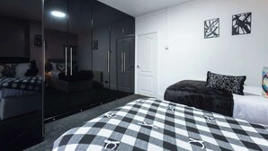 Un dormitorio con una colcha a cuadros, un armario con espejo y arte abstracto en la pared.