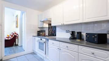 Una cocina moderna con armarios blancos, estufa a gas y cafetera.