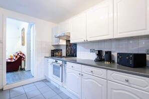 A modern kitchen with white cabinetry, a gas stove, and a coffee maker. - 4 Bedrooms Home Close to Shops, A63 Saltend Hull (Kingston Upon Hull)