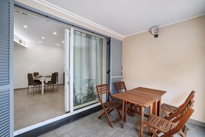 Zona pranzo con tavolo e sedie, una porta scorrevole in vetro che dà su un'altra stanza e un lampadario.