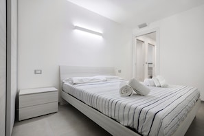 Une chambre à coucher moderne avec un lit, une table de chevet et un miroir.