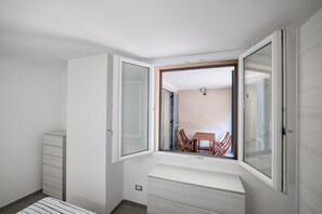 Une pièce de taille modeste dotée d’une porte coulissante donnant sur un coin repas, d’une banquette intégrée et d’un petit meuble de rangement.