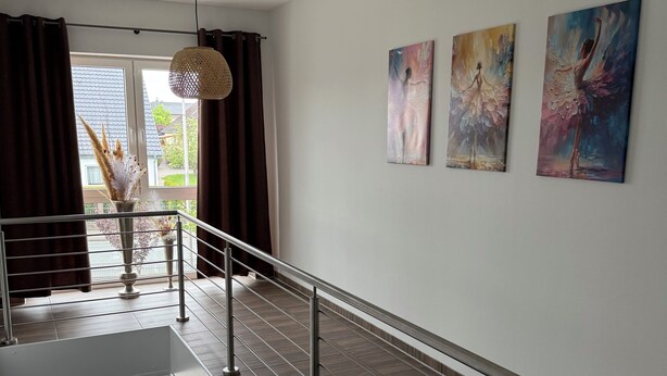 Un interior moderno con una escalera, barandilla y obras de arte en las paredes.