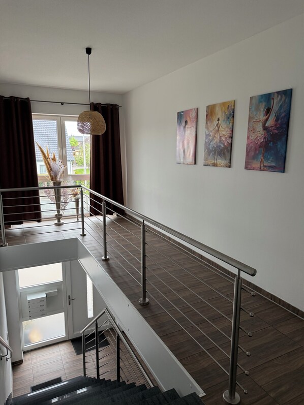 A modern interior with a staircase, railing, and artwork on the walls.
