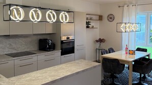 Una cocina moderna con horno empotrado, cafetera y comedor con mesa y sillas.