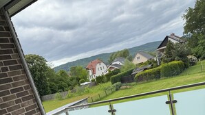 Un balcón con mesa y sillas, con vista a una masa de agua y casas.