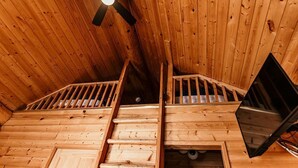 A wooden interior with a ceiling fan, a staircase, and a bed. - Riverside RV Resort (Whistler)