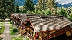 A row of log cabins with wooden balconies and a pathway leading to them. - Riverside RV Resort (Whistler)